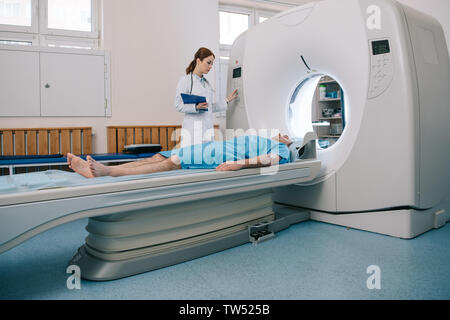 Junge Röntgenassistenten, die CT-Scanner während der Vorbereitung des Patienten für die Tomographie Stockfoto