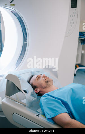 Schöner Mann liegen auf CT-Scanner Bett, während in der Tomographie test Stockfoto