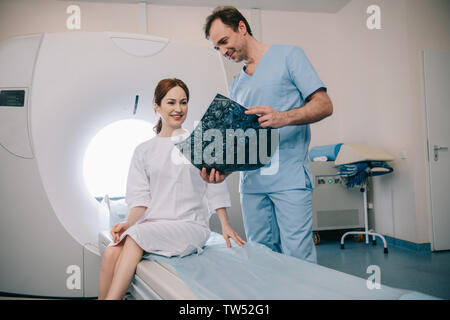 Lächelnd Radiologen x-ray zeigen Ergebnisse zu Happy attraktive Frau Stockfoto