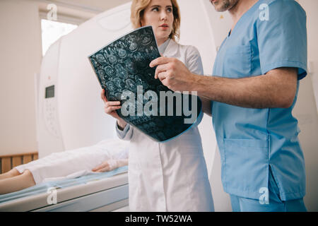 7/8-Ansicht der Arzt prüft Tomographie Diagnose zusammen mit Radiologen Stockfoto