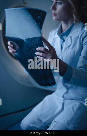 Nachdenklich Arzt holding Röntgendiagnostik während der Sitzung auf Computertomograph Stockfoto