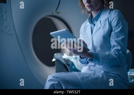 Teilansicht der Radiologe Holding digital Tablet mit x-ray Diagnose beim Sitzen in der Nähe des CT-Scanners Stockfoto