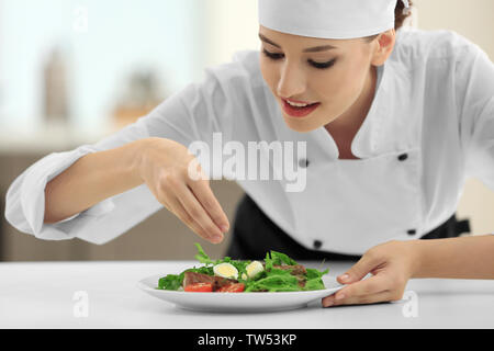 Junge Köchin Salzen leckeres Gericht in der Küche Stockfoto