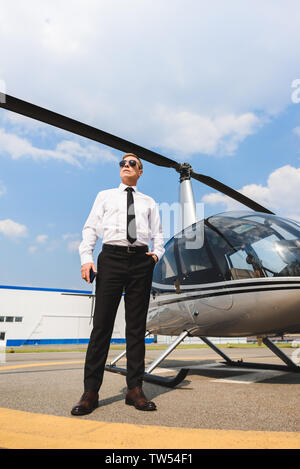 Low Angle View von Pilotprojekten in formalen Verschleiß und Sonnenbrille in der Nähe von Hubschrauber Stockfoto