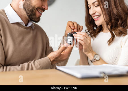 Selektiver Fokus der glückliche Frau an dem Schlüssel in die Hände der bärtige Mann auf der Suche Stockfoto