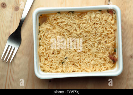 Pflegende Nudeln auf einem hölzernen Tisch in einer Wegwerf- Platte. Stockfoto