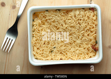 Pflegende Nudeln auf einem hölzernen Tisch in einer Wegwerf- Platte. Stockfoto