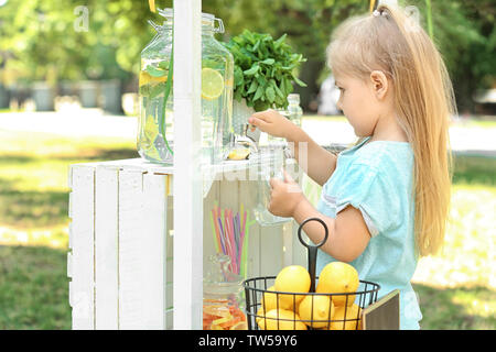 Kleines Mädchen gießen Limonade aus Glas mit in Park tippen Stockfoto