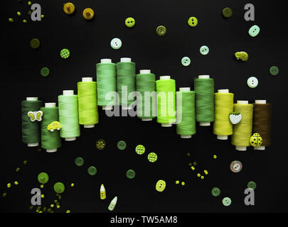 Grüne Komposition mit Gewinde und Schaltflächen auf schwarzem Hintergrund Stockfoto