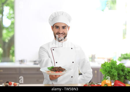 Junge männliche Chef Holding frisch zubereitetes Gericht in der Küche Stockfoto