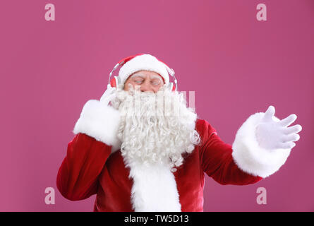 Santa Claus das Hören von Musik auf farbigen Hintergrund Stockfoto