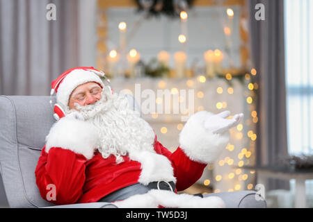 Santa Claus das Hören von Musik im Wohnzimmer Stockfoto