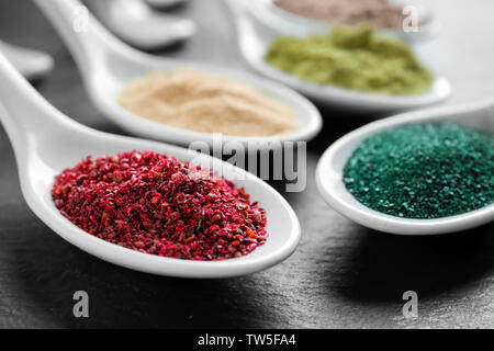 Maqui Berry und spirulina Pulver in weißer Keramik Löffel auf schwarzem Hintergrund Stockfoto