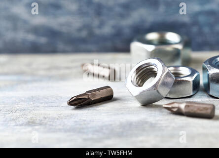 Sechskantmuttern und Bits für einen Schraubendreher auf Holz- Hintergrund. Close Up. Kopieren Sie Platz. Stockfoto