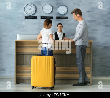 Junges Paar an der Rezeption im Hotel Stockfoto