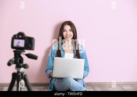 Junge Frau Aufnehmen von Videos in der Nähe der Farbe Wand Stockfoto
