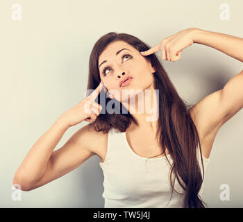 Junge schönes Mädchen zeige Finger gun Geste, selbst schießen und oben zu schauen. Closeup getönten portriat Stockfoto