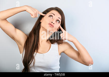 Junge schönes Mädchen zeige Finger gun Geste, selbst schießen und sich auf blauem Hintergrund. Closeup portriat Stockfoto