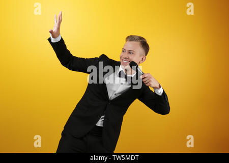 Junge Presenter mit Mikrofon auf farbigen Hintergrund Stockfoto