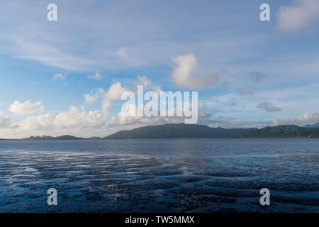 Blauer Himmel und weiße Wolken in einem Muster von Wasser Wege reflektiert durch Wattenmeer unter bewaldeten Bergen und Hügeln an der Küste von Oregon in der Nähe von Tillamo Stockfoto