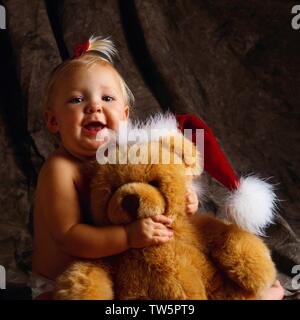 Santa Baby mit Teddybär Stockfoto