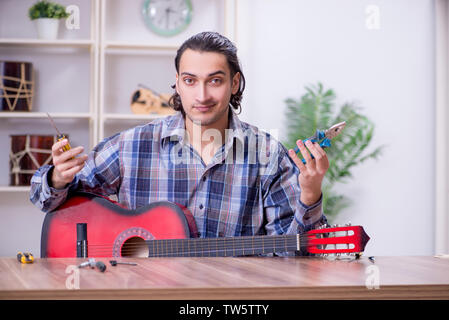 Junge schöne Handwerker Reparatur Gitarre Stockfoto