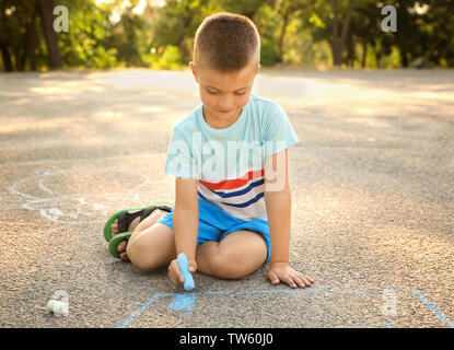 Cute little boy Zeichnen mit Kreide, im Freien Stockfoto