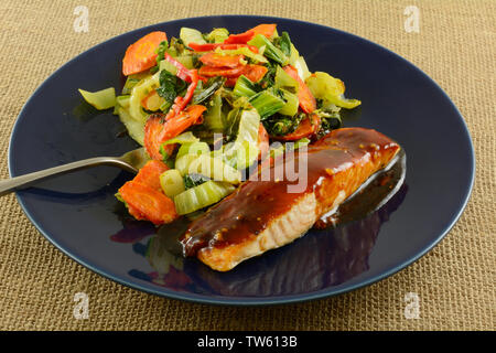 Gebackenen Lachs Fisch Filet mit Teriyaki-sauce und Gemüse auf blaue Platte mit Gabel Stockfoto
