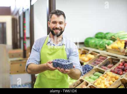 Bestseller Schürze holding Kunststoffbehälter mit blaubeeren am Markt Stockfoto