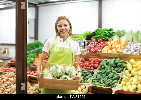 Junge Verkäuferin holding Holzkiste mit Blumenkohl am Markt Stockfoto
