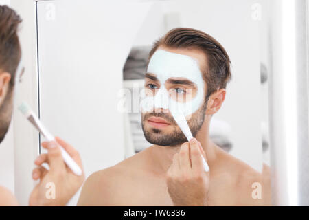 Jungen gutaussehenden Mann Auftragen kosmetischer Maske auf Gesicht in Bad Stockfoto