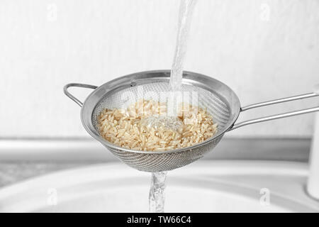 Waschen roher Reis mit Wasser in der Küche Stockfoto