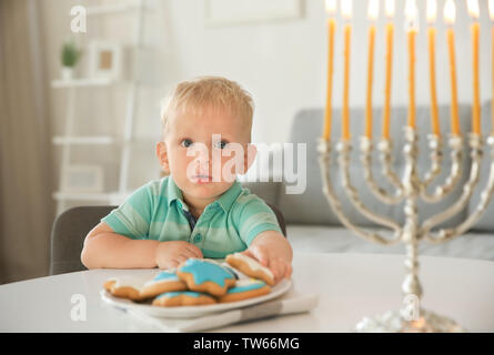 Jüdischen Jungen essen festliche Hanukkah cookies zu Hause Stockfoto