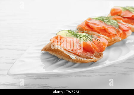 Leckere kleine Sandwiches mit Lachs und Gurke auf Platte Stockfoto