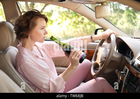 Frau trinkt Alkohol im Auto. Stockfoto