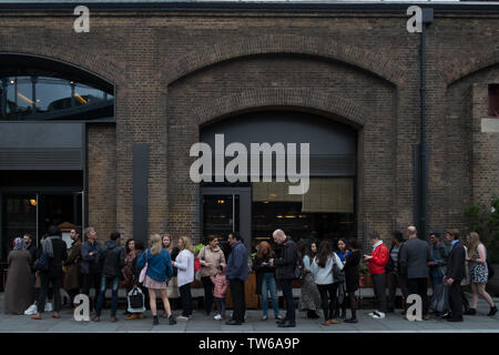 Die Menschen in der Warteschlange außerhalb einer belebten Restaurant (Dishoom King's Cross) im Getreidespeicher Square, London, UK. Stockfoto