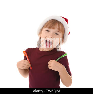 Süße kleine Mädchen in Santa Hut mit Zuckerstangen auf weißem Hintergrund. Weihnachten Konzept Stockfoto