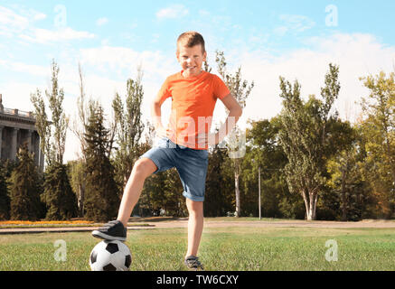 Süße Junge mit Fußball auf Rasen Stockfoto