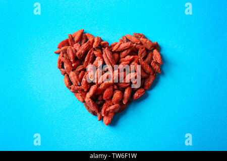 Herz aus Goji Beeren auf farbigen Hintergrund Stockfoto