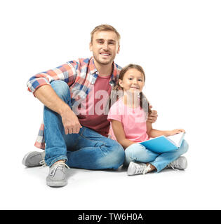 Junger Mann und seine kleine Tochter lesen Buch auf weißem Hintergrund Stockfoto