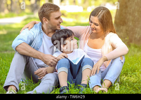 Glückliche Familie Lesung buchen Sie im Park Stockfoto