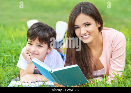 Junge Frau und ihr kleiner Sohn das Lesen von Büchern in Park Stockfoto
