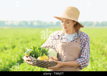 Frau Bauer Holding wicker Schüssel mit Gemüse im Feld Stockfoto