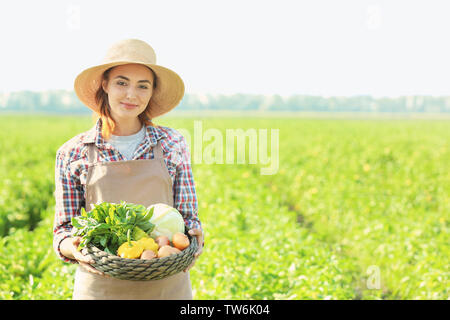 Frau Bauer Holding wicker Schüssel mit Gemüse im Feld Stockfoto