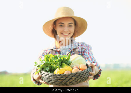 Frau Bauer Holding wicker Schüssel mit Gemüse im Feld Stockfoto