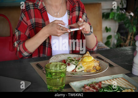 Junge Frau, Foto, köstliches Essen mit Handy am Tisch Stockfoto