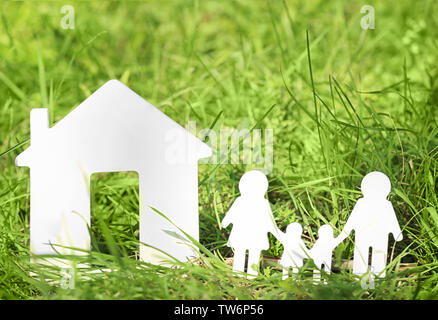 Holzfigur von Familie mit Haus auf grünem Gras Stockfoto