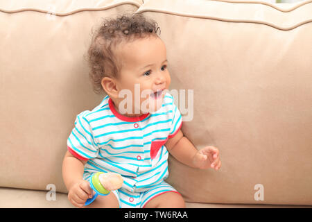 Süße kleine African American Baby mit Nibbler auf dem Sofa Stockfoto