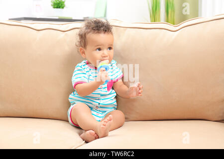 Süße kleine African American Baby mit Nibbler auf dem Sofa Stockfoto