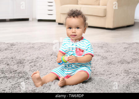 Süße kleine African American Baby mit Nibbler auf dem Teppich Stockfoto